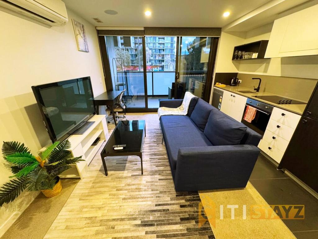a living room with a blue couch and a tv at Braddon Base in The Midnight, Heated Pool & Sauna in Braddon