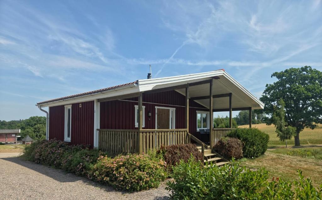 a small red house with a porch on a field at Sjötorps säteris stugby in Larv