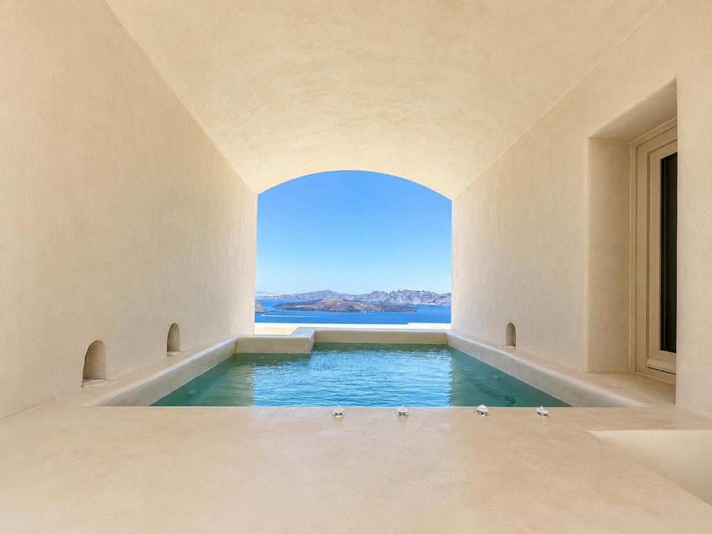 a swimming pool in a room with a view of the ocean at Vespera Private Luxury Suites in Santorini