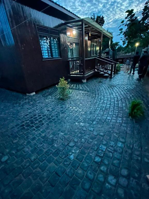 a house with a brick walkway next to a building at Embawwo Rustic Cabin in Entebbe