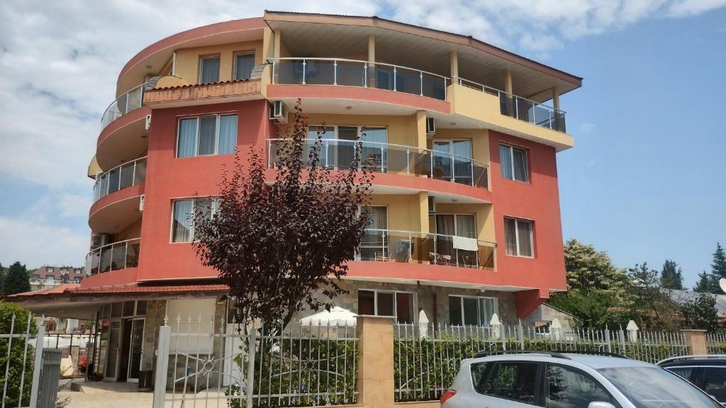 a red building with cars parked in front of it at Sunny Flower Family Hotel in Sunny Beach
