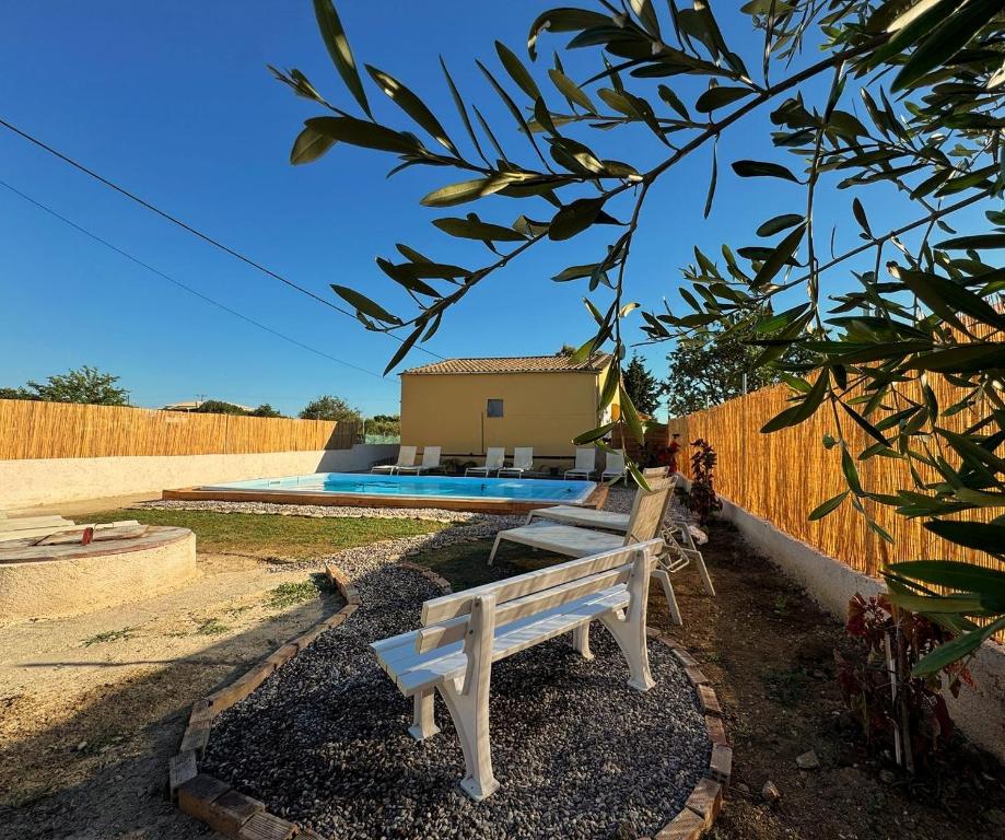 a white bench sitting in a yard with a pool at Antilia corfu 4 in Agios Georgios
