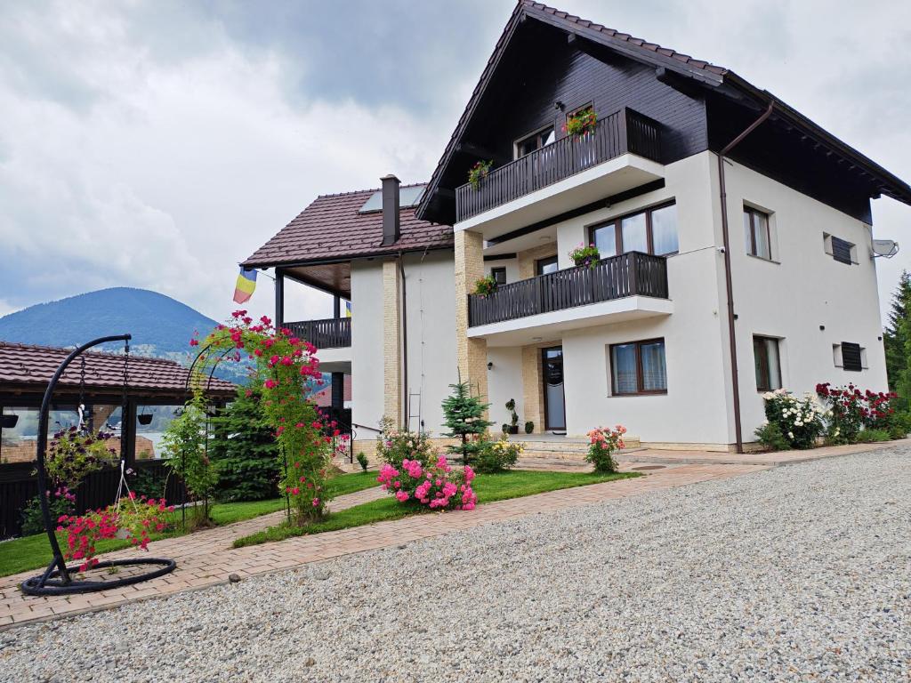 a large white house with flowers in front of it at Aqualina Colibita - pe malul lacului in Colibiţa