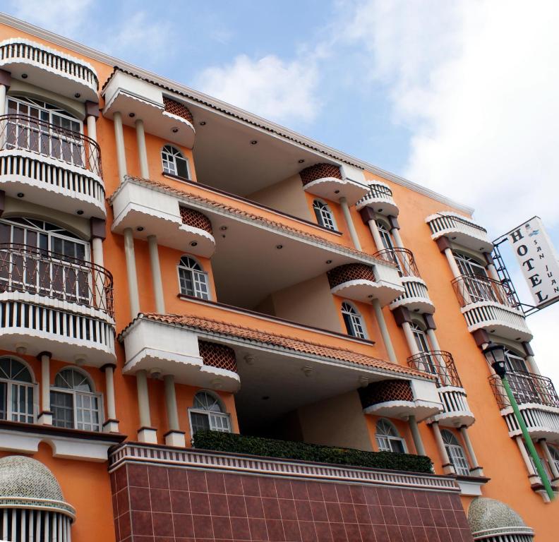 ein orangefarbenes Gebäude mit Balkonen und einer Uhr darauf in der Unterkunft Hotel San Juan Centro in Villahermosa