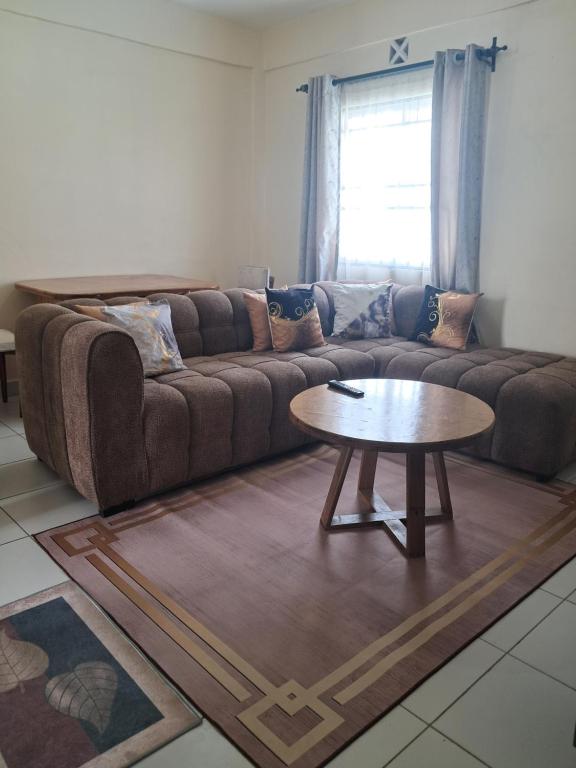 a living room with a couch and a table at Cozy 2 BR with 3 Beds, AC & Hot Shower at Buxton Point Apartments Off RG Road Gate A in Mombasa