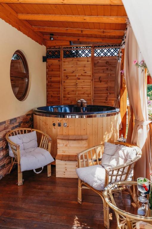 a room with a tub with two chairs and a table at Domki & Jacuzzi w Centrum Soliny 885-053-839 in Solina