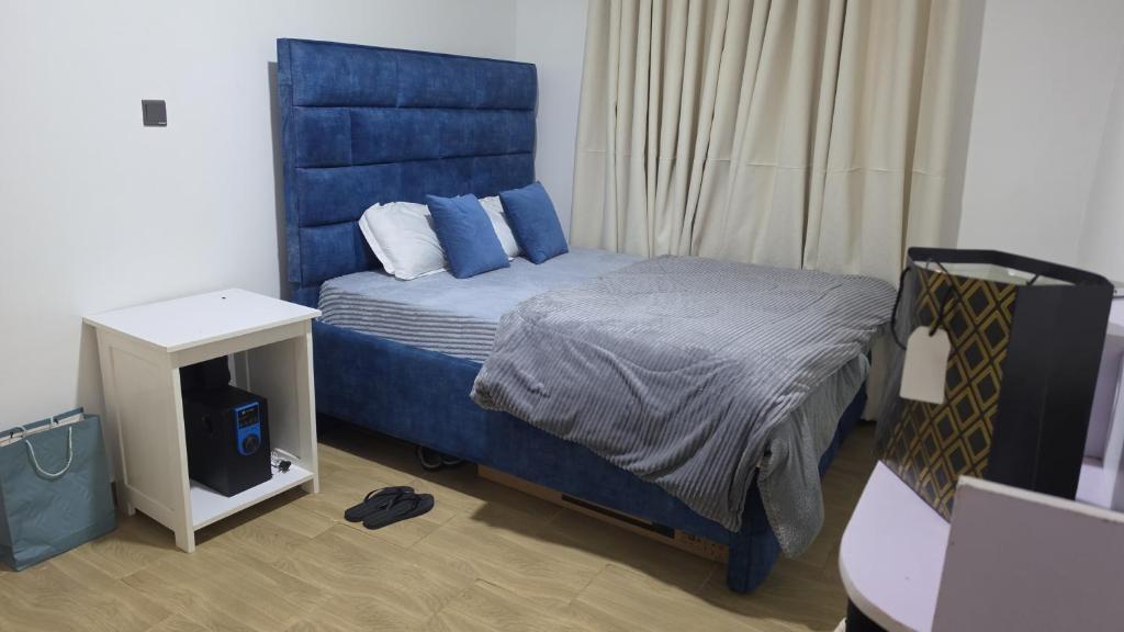 a bedroom with a bed with a blue headboard at Crane Suites in Eldoret