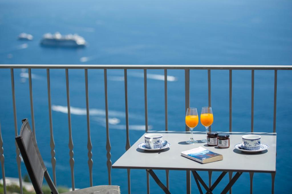a table with two glasses of orange juice on a balcony at Villa Alba - Amalfi Coast in Amalfi