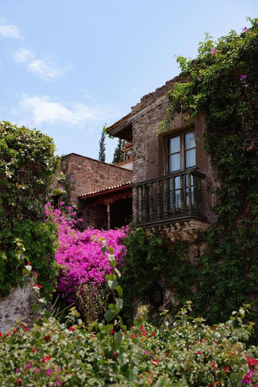 a stone house with pink flowers in front of it at Hacienda Las Amantes in San Miguel de Allende