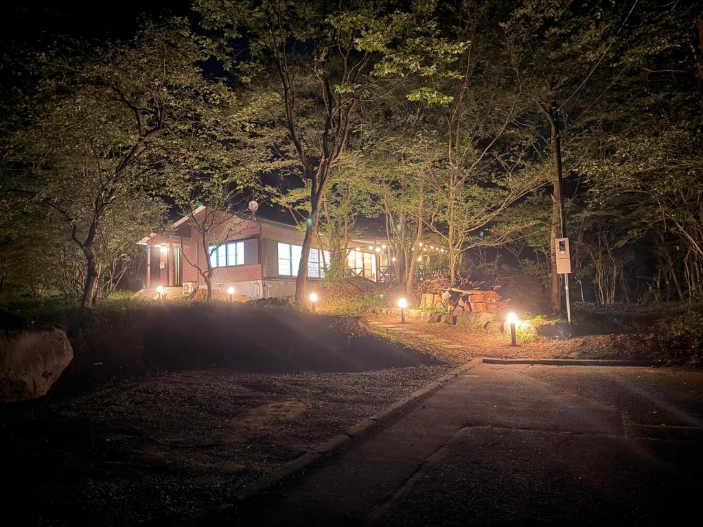 a house with lights in front of it at night at BBQ屋根付き大型ウッドデッキ川のせせらぎを聴きながら贅沢時間ペット同伴OK森と音に癒されるコテージ Rill in Nasu