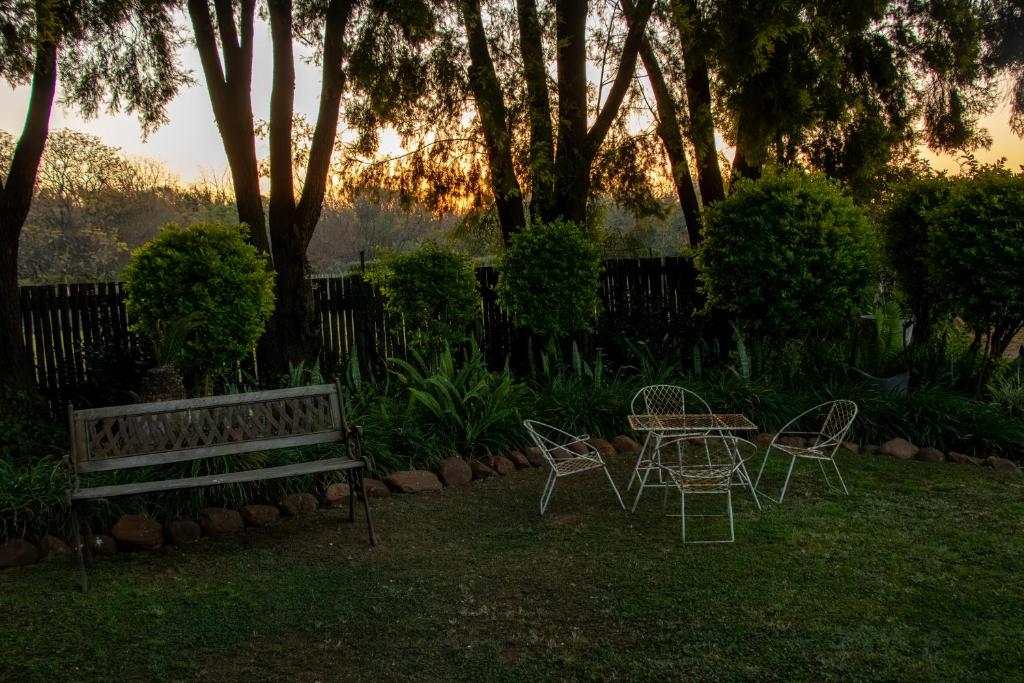 a table and chairs and a bench in a yard at Adem Gasteplaas & Function Venue in Kroondal