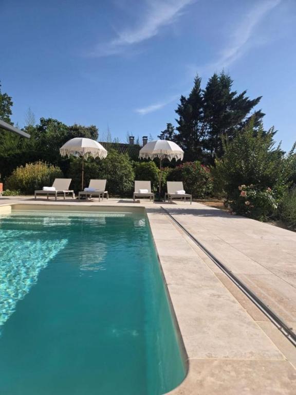a swimming pool with two chairs and umbrellas at La Villa Blateiras in Générargues