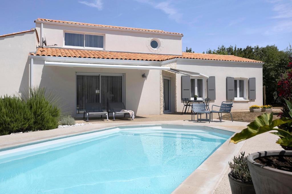 a villa with a swimming pool in front of a house at Les Chambres De Miloly in La Jarrie