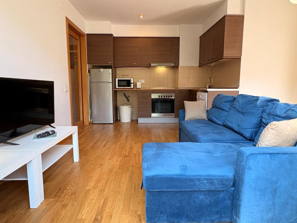 a living room with a blue couch and a kitchen at Con encanto, buena ubicación, confort y parking - Aüt 2 in Pla de l'Ermita