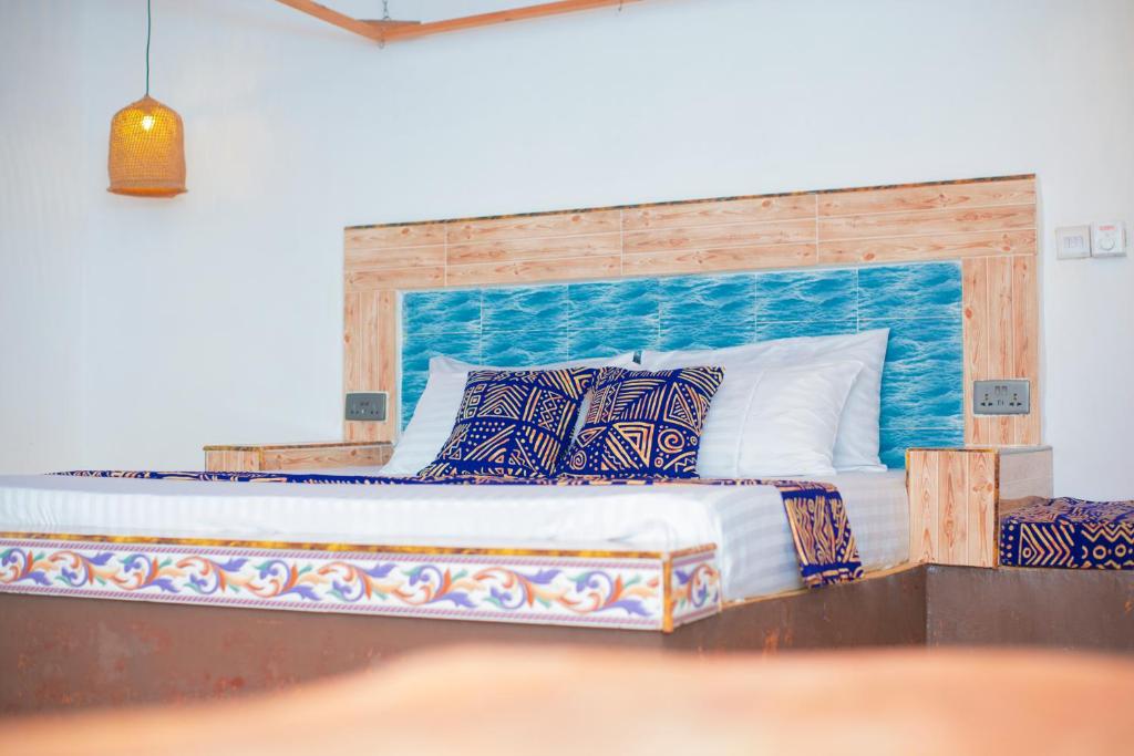 a bedroom with a large bed with a wooden headboard at Bahari Studio Apartment in Bwejuu