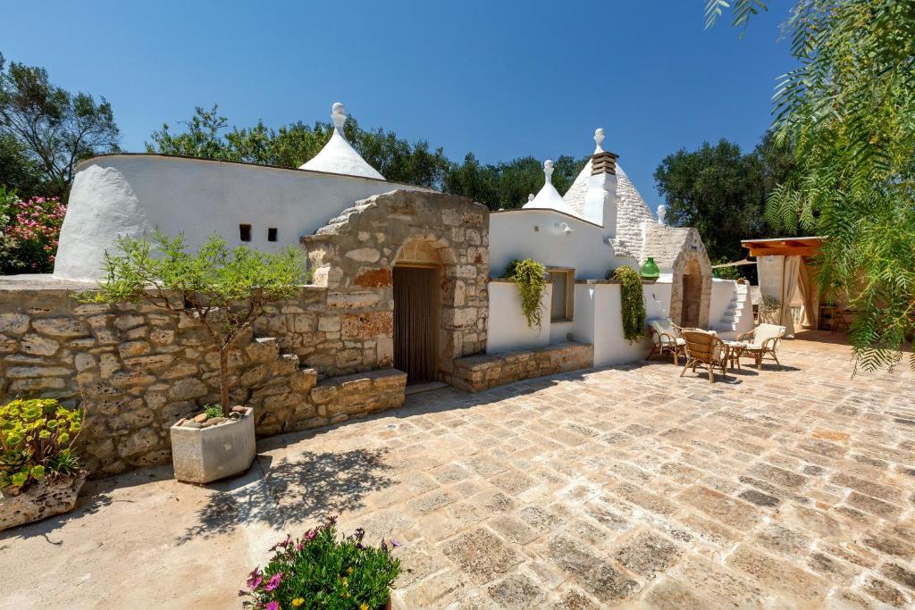 a patio of a house with a stone wall at Trullo Sobba Llera by BarbarHouse in San Michele Salentino