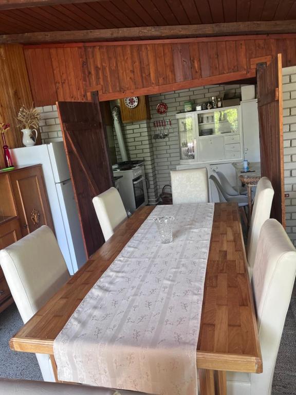 a dining room table with white chairs and a kitchen at Kuća za odmor Sremac in Apatin