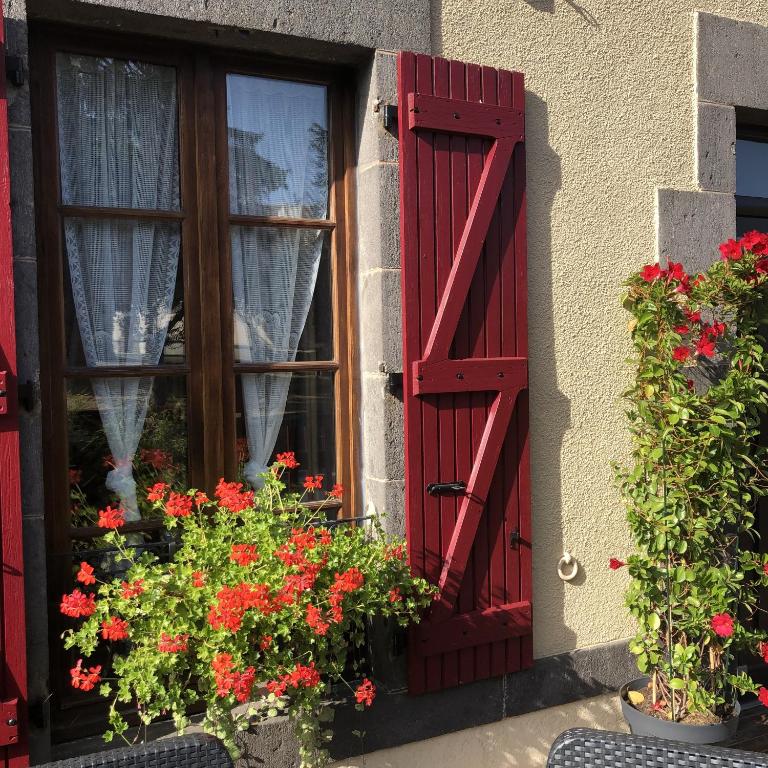 a window with red shutters and flowers in a window at A l'Aube des Volcans in Charbonnières-les-Vieilles