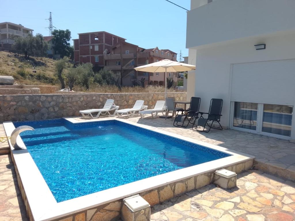 a swimming pool with chairs and an umbrella on a patio at Lux Villa Azur in Bar