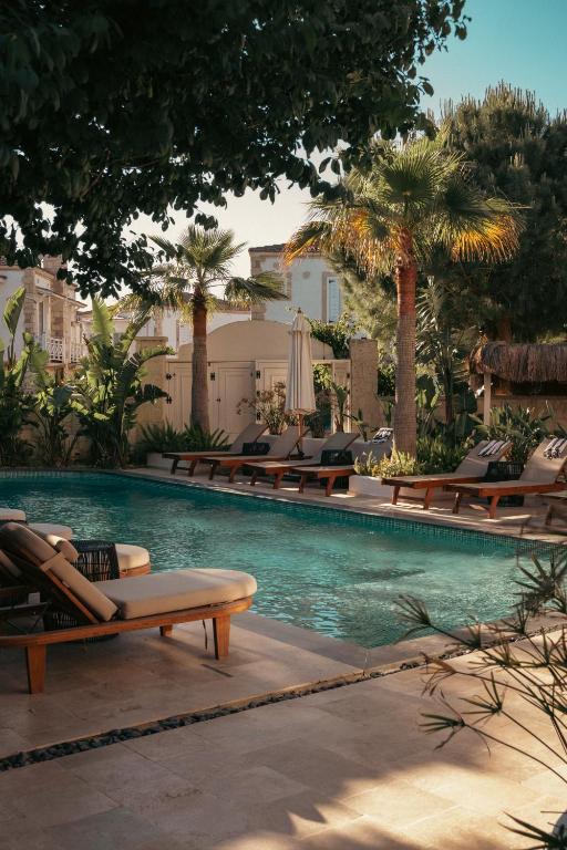 ein Swimmingpool mit Liegestühlen und Palmen in der Unterkunft Art otel in Alacati
