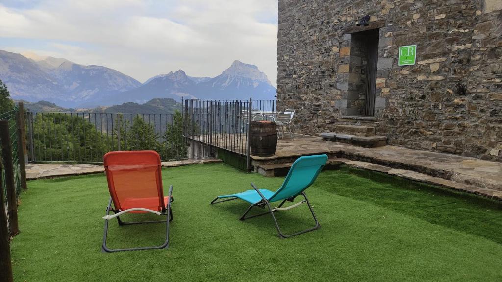 two chairs sitting on a lawn with mountains in the background at Casa Rural Chuan Murillo in Bestué