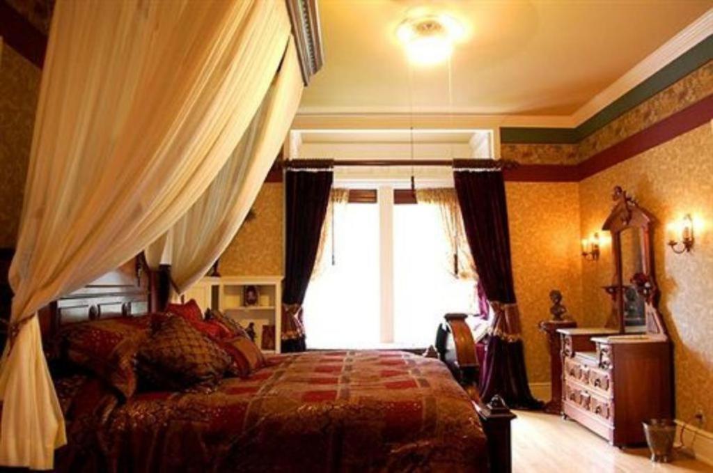 a bedroom with a bed and a window with curtains at Alexander Mansion Bed and Breakfast in Winona