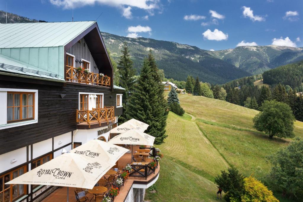 ein Hotel mit Tischen und Sonnenschirmen auf einem Balkon in der Unterkunft Hotel Zátiší in Špindlerův Mlýn