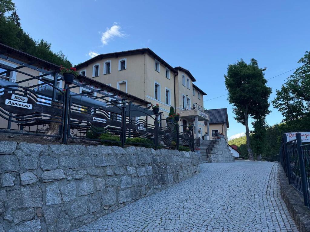 a stone wall next to a building on a street at Willa Agnieszki in Jagniątków