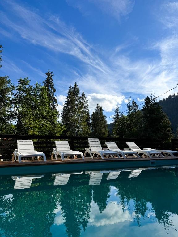 a group of chairs sitting next to a swimming pool at Котеджі Сім Вітрів in Volosyanka