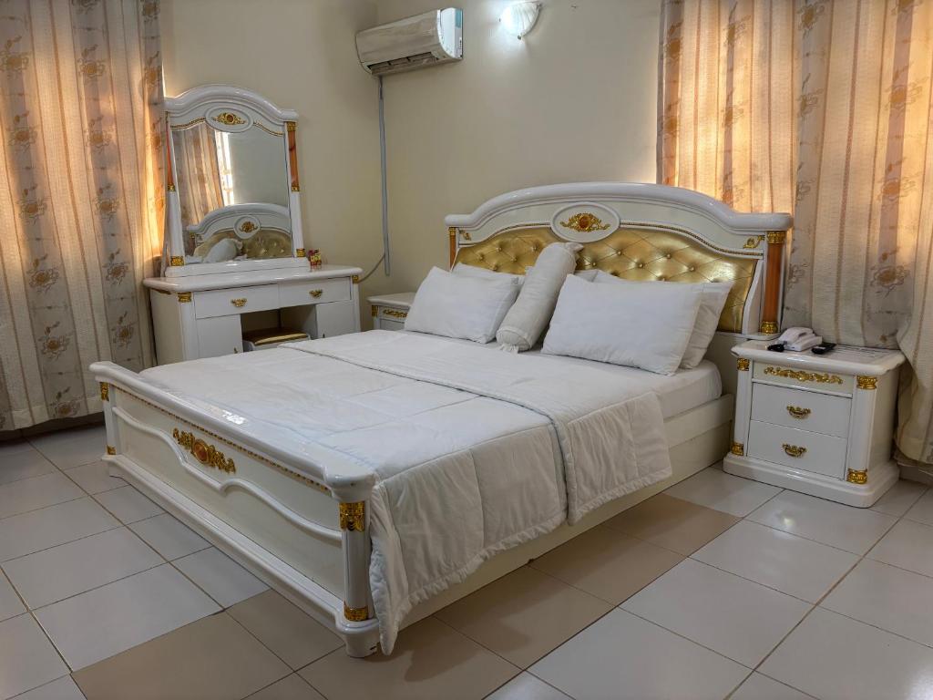 a bedroom with a white bed and a mirror at Christabel Hotel and Apartment Rayfield Jos in Jos