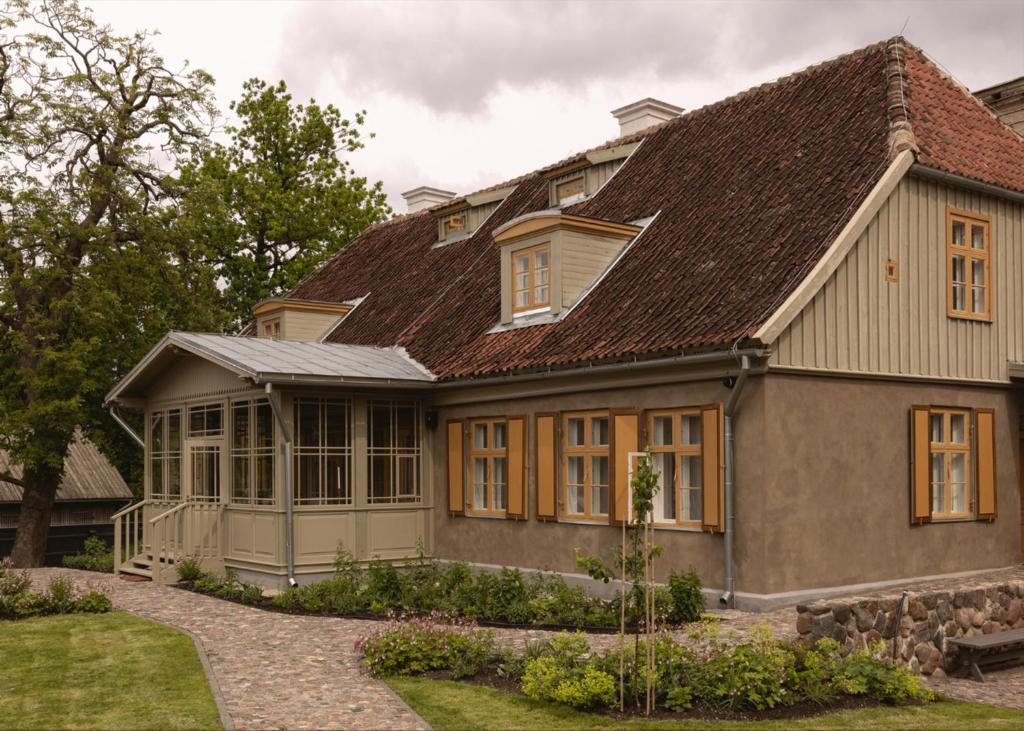 a house with a brown roof and a yard at Ausma Hotel in Kuldīga