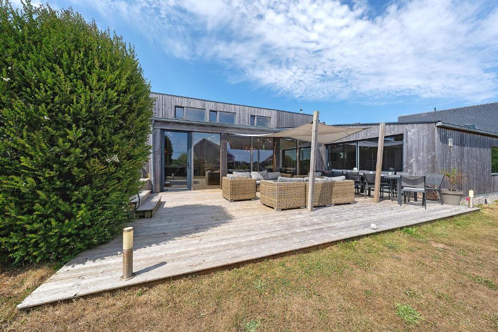 a wooden deck with chairs and a tent in front of a building at La villa Grand Ouest in Plounéour-Trez