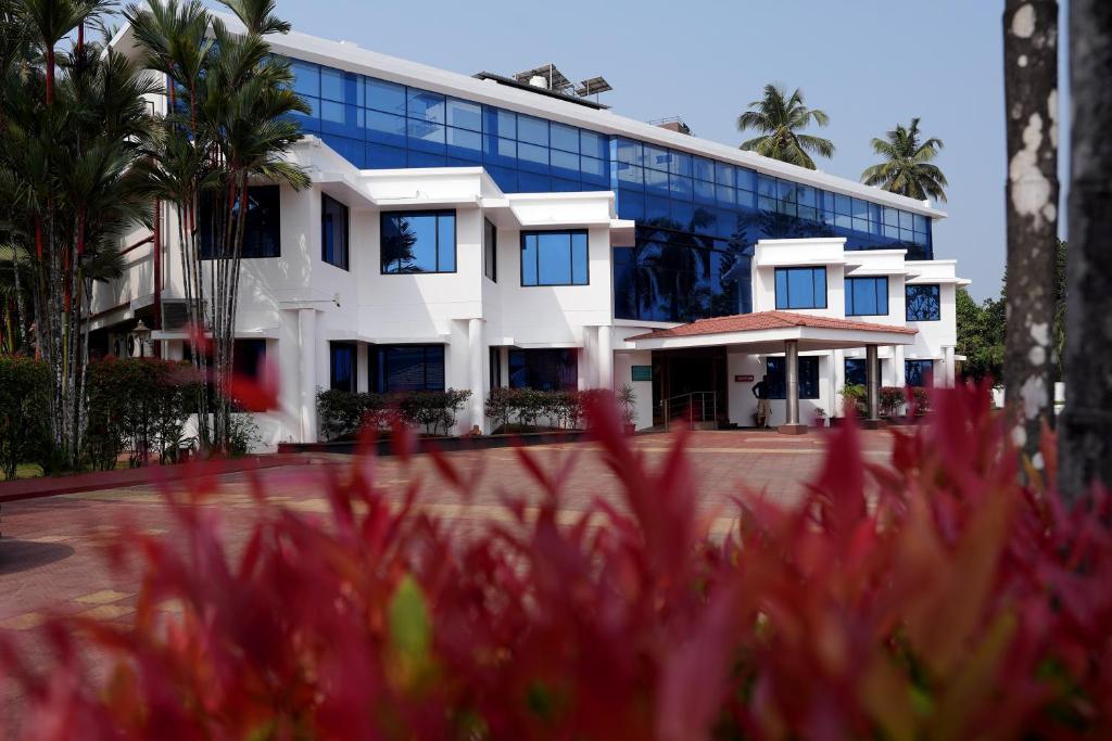 a white building with blue windows and pink flowers at KRISHNA HOLIDAY VILLAGE in Trichūr