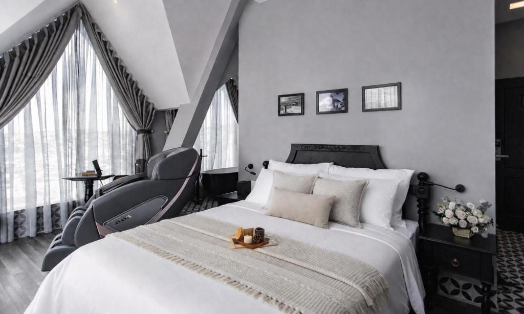 a bedroom with a bed and a chair and windows at TTR Skypool View Hotel - Đà lạt in Da Lat