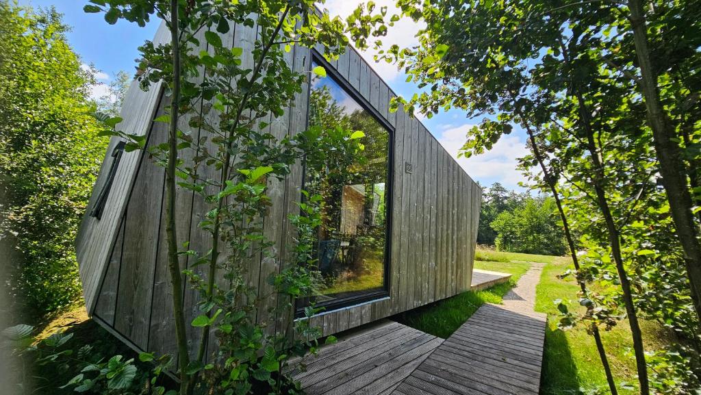 a house clad in wood with large glass windows at Tiny house De Wylp in Westergeest