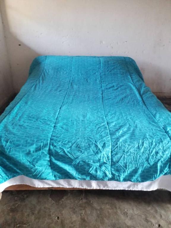 a bed with a blue blanket on top of it at Mabuu Drive Inn in Waya