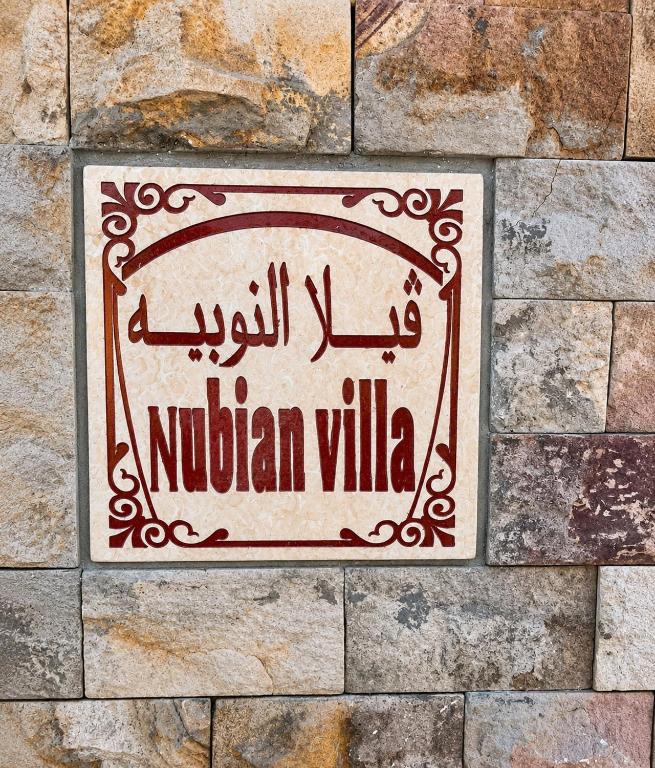 a sign on the side of a stone wall at Nubian Villa with Private Pool in Naj‘ al Aḩwāl
