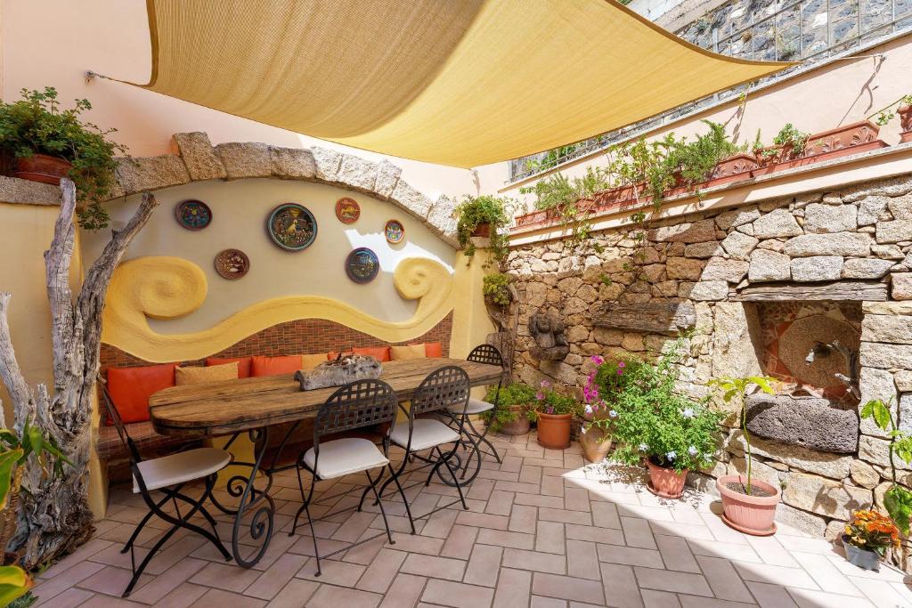 a patio with a table and chairs and a stone wall at Camera a Dorgali al B&B Sa Madalena in Dorgali