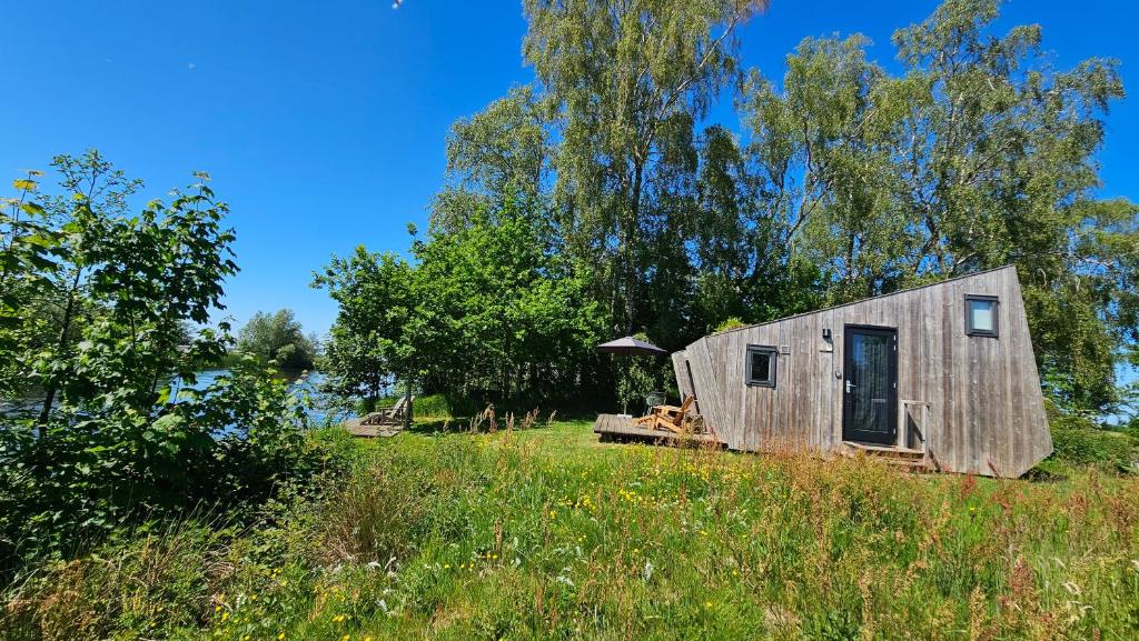 a small wooden cabin in a field with trees at Tiny house De Ljip in Westergeest