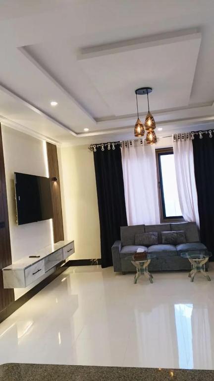a living room with a couch and a flat screen tv at Dreamer Guest house in Nathia Gali