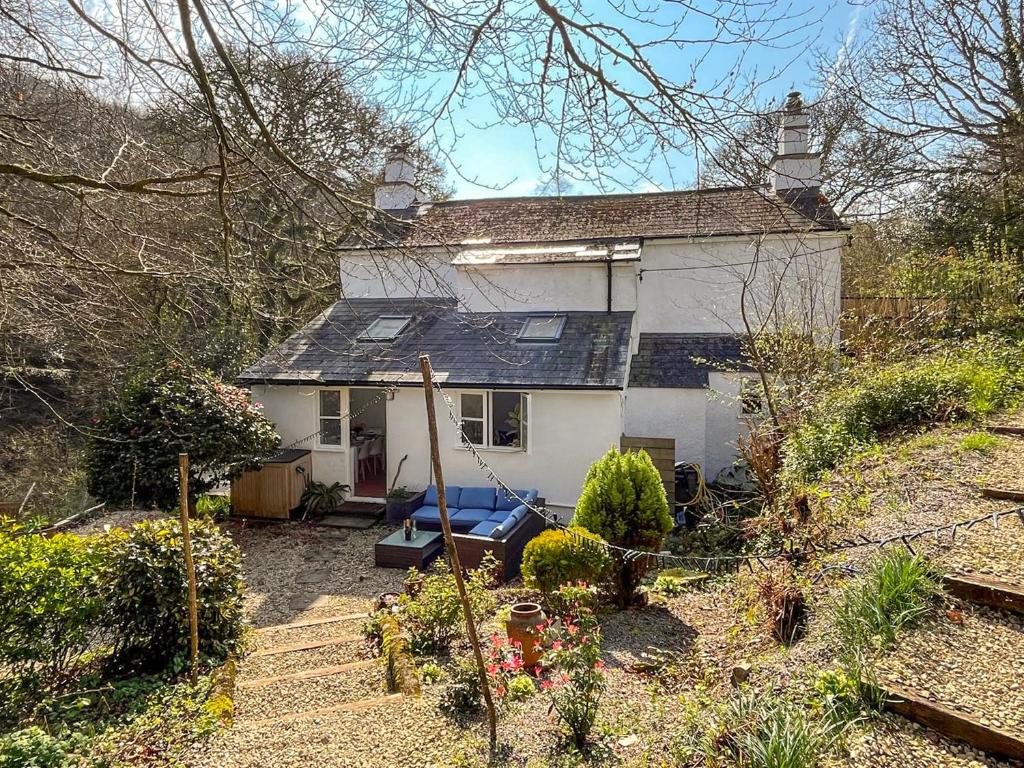 a small white house in the middle of a garden at Gara Mill Cottage in Kingsbridge