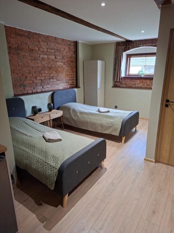 a bedroom with two beds and a brick wall at Mõisa Ait Stuudiokorterid in Võru