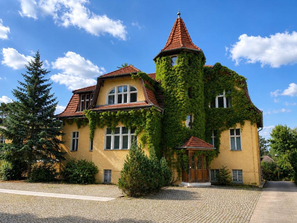 a building covered in ivy on a street at Villa am Peetzsee Unterkunft am See in Grünheide mit Parkplatz, Self Check-in, Küche, WLAN, Nähe Tesla Berlin in Schlangenluch