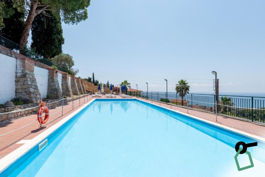 a person sitting in a swimming pool with the ocean in the background at Hotiday Bordighera in Bordighera