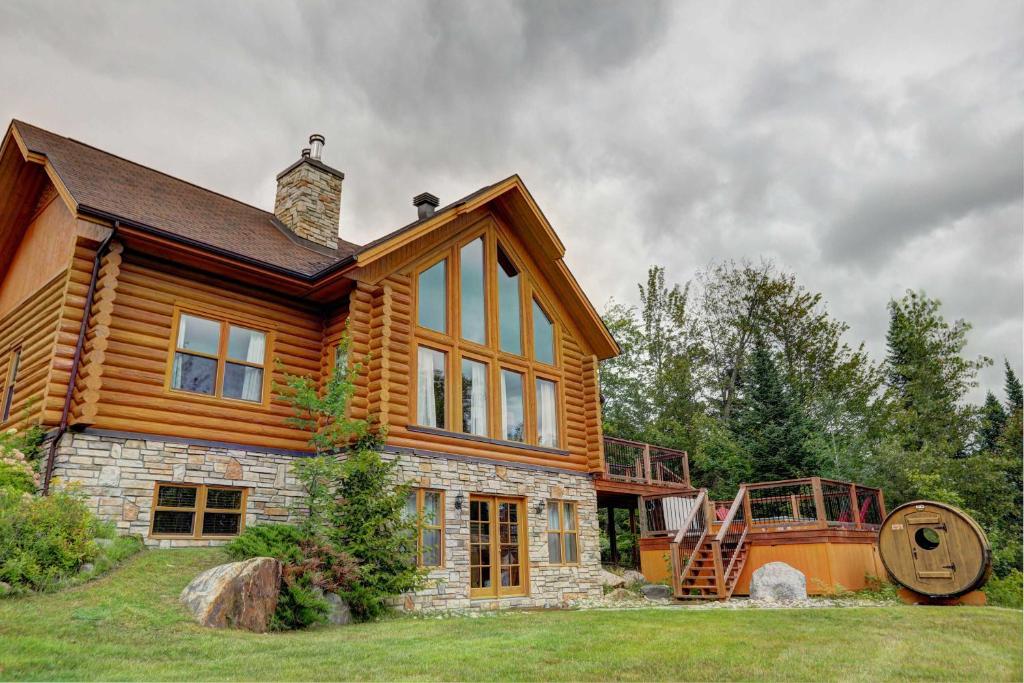 a log home with a staircase on the side of it at Spa Pool & Sauna - Laurentides Serenity in Mille-Isles