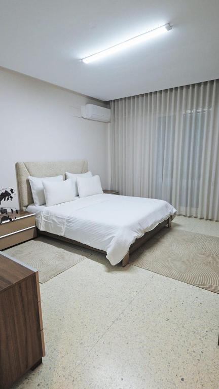 a bedroom with a large white bed and a window at Chez-moi in Sfax