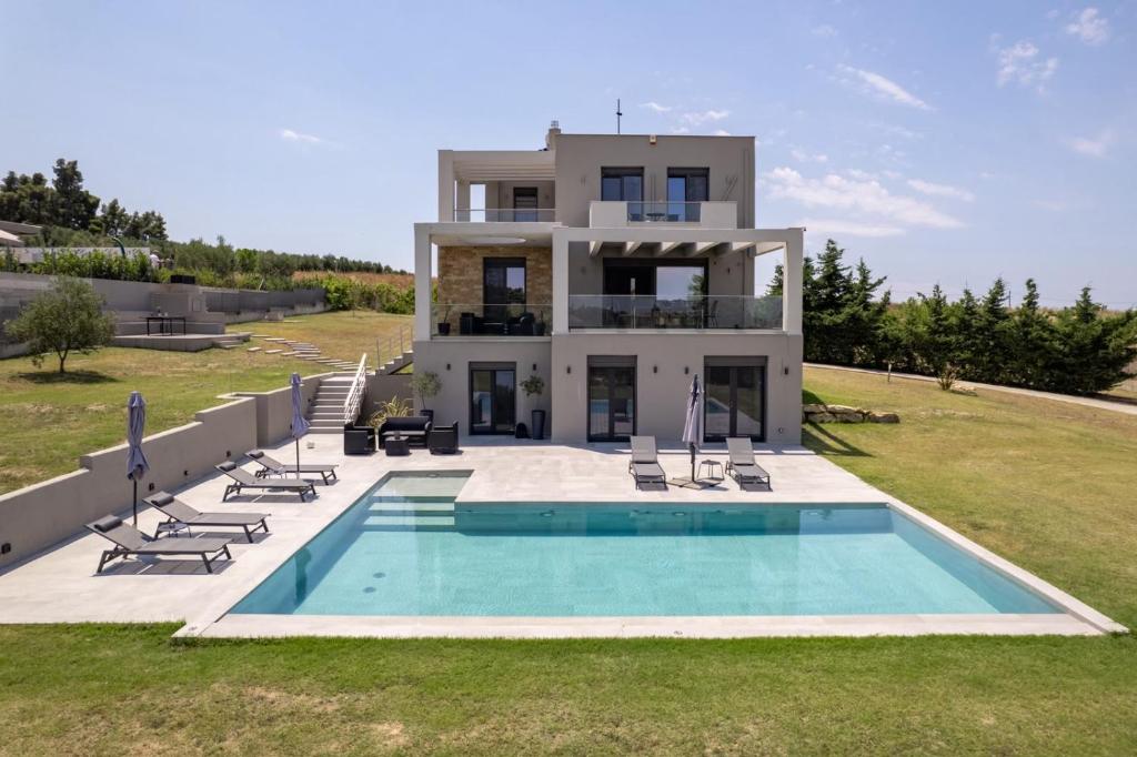 a villa with a swimming pool in front of a house at Sani Invictus Villa in Sani Beach