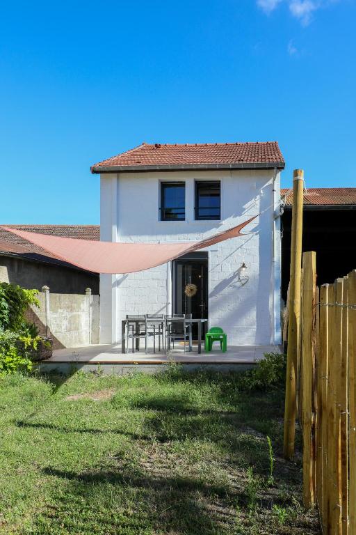 a white house with a hammock in front of it at Gîte les clés de l'émeraude in Bergnicourt