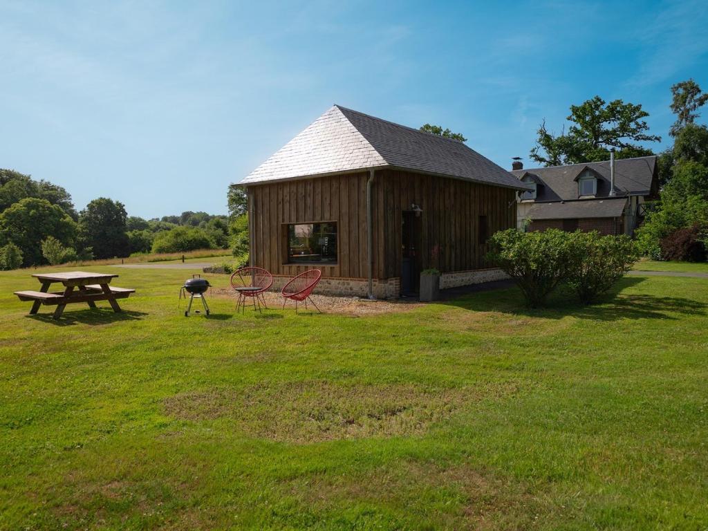 a wooden cabin with a picnic table and a grill at La Petite Maison De Rose in Flancourt-Crescy-en-Roumois