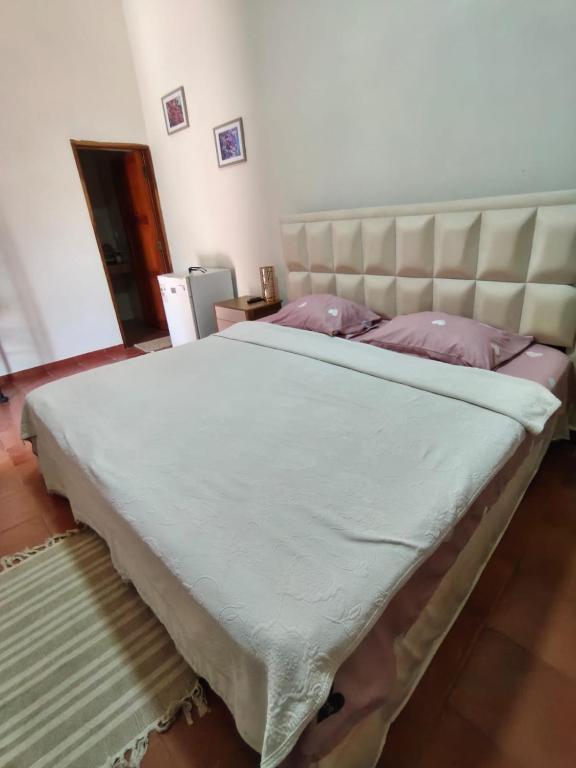 a large bed in a bedroom with a large headboard at Raices Boulevard Hotel in Portachuelo